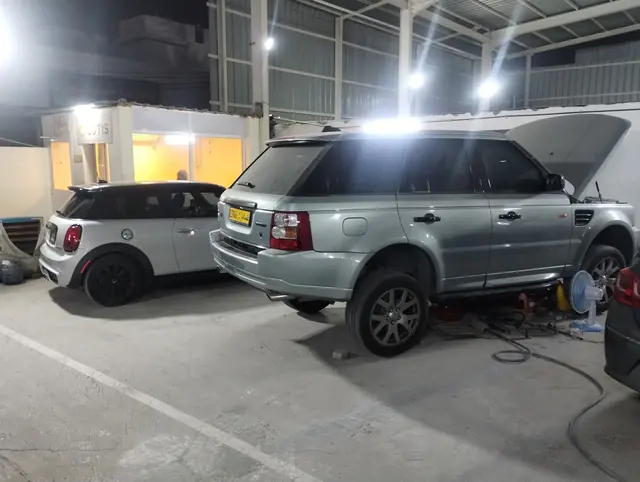 Range Rover Sport on stands beside a Mini during servicing